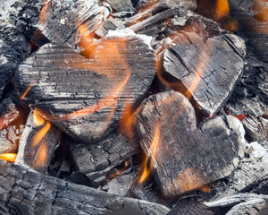 Hot coals and burning woods in the form of human heart. Glowing and flaming charcoal, bright red fire and ash. .Close-up, top view.