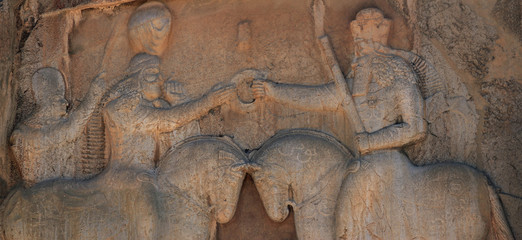 Obraz premium Detail of a stone decoration in a tomb ruin of the ancient necropolis Naqsh-e Rostam, that shows the triumph of Shapur over the Roman Emperor Valer. Iran