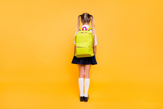 Full length, legs, body, size back behind rear view photo of girl in blue skirt with yellow lemon rucksack small girl isolated on bright yellow background with copy space for text