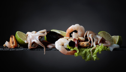Mixed delicious seafood with salad and lime slices .