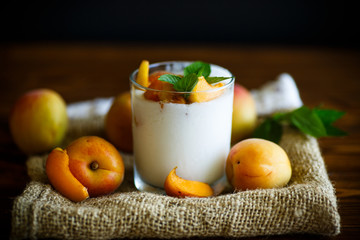 homemade yogurt with ripe apricots on wooden table