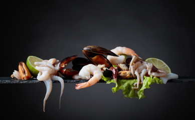 Mixed delicious seafood with salad and lime slices .