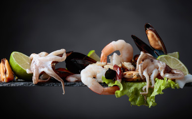 Mixed delicious seafood with salad and lime slices .