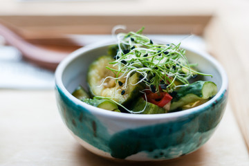 Traditional Asian food. Kimchee from cucumber pepper and cabbage, decorated with sprouts in a ceramic bowl. Korean food.