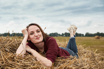 Naklejka na ściany i meble young girl having fun in the field, lying on a haystack