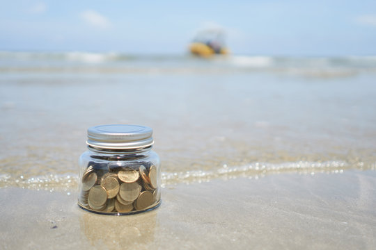 Gold Coin In Bottle On Soft Wave Of Blue Ocean On Sandy Beach, Growth For The Save Money Concept