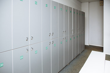 Row of steel lockers with white bench.