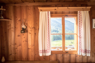 Fenster mit bunten Vorhängen in Holzhütte