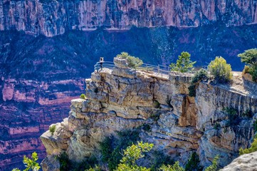 A woman overlooks the Grand Canyon on a windy summer day