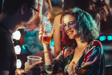 Young woman at the festival drinking beer with boyfriend  - obrazy, fototapety, plakaty