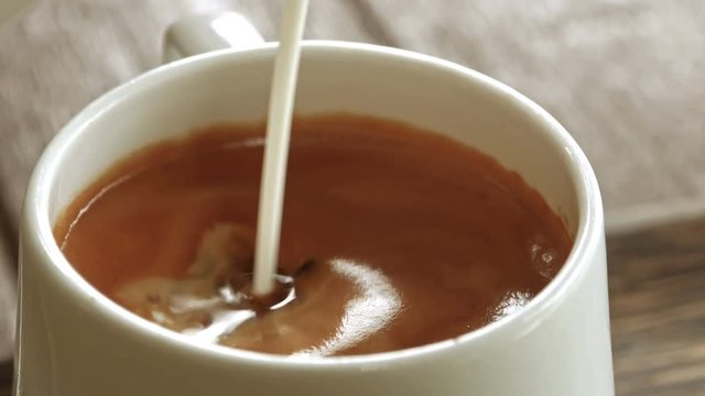 Pour milk on a glass of coffee.
