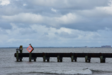 Pipe with "danger" sign jutting out over the ocean