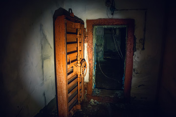 Large steel hermetic door of airlock in abandoned Soviet bunker in flashlight light