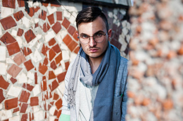 Dreamer stylish macho man in gray suit, scarf and glasses posed on the roof.