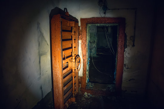 Large steel hermetic door of airlock in abandoned Soviet bunker in flashlight light