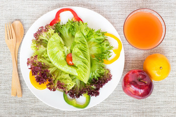 Fresh vegetables salad in white plate with apple and juice 