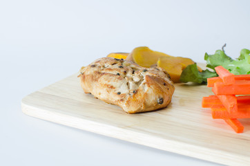chicken steak on wood plate with carrot salad and pumpkin on white background