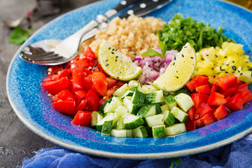Salad with quinoa, arugula, sweet peppers, tomatoes and cucumber in bowl on a dark background. Healthy food, diet, detox and vegetarian concept. Buddha bowl.