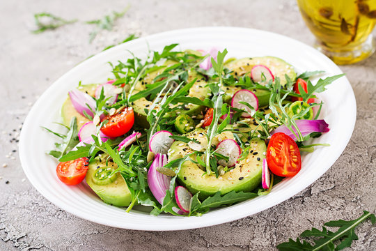 Diet menu. Healthy salad of fresh vegetables - tomatoes, avocado, arugula, radish and seeds on a bowl. Vegan food.