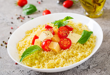 Millet porridge with cheese, butter and basil in white bowl. Tasty food. Breakfast.
