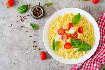 Millet porridge with cheese, butter and basil in white bowl. Tasty food. Breakfast. Top view. Flat lay