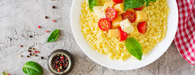 Millet porridge with cheese, butter and basil in white bowl. Tasty food. Breakfast. Banner. Top view. Flat lay