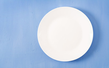 Top view of blank white dish on a blue background. Copy space. Mockup