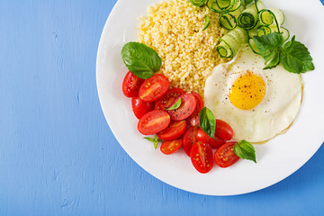 Healthy breakfast. Dietary menu. Millet porridge and tomato, cucumber salad and fried eggs. Top view. Flat lay