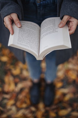 Naklejka na ściany i meble The girl holding in her hands open book. Birds eyes shot. High angle shot. Autumn. Outdoor