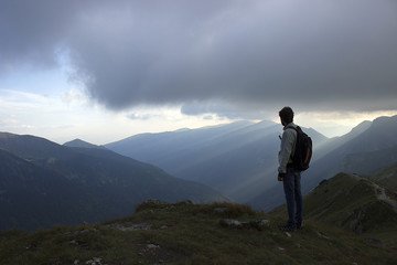 Obraz premium A male mountaineer looking over a vast, rocky, mountainous sunrise scene.