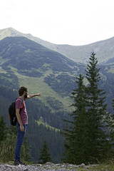 Naklejka premium a man in a T-shirt stands sideways and shows the way to the mountains, Move forward, way up