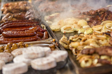 Assorted delicious grilled meat, sausage, potatos with vegetables and cheese on a barbecue