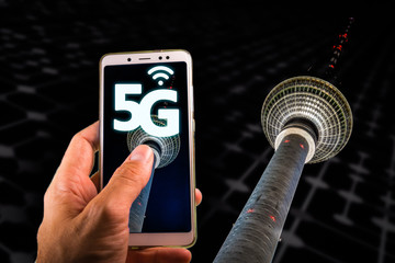 Smartphone with 5G on screen and Famous Berlin television tower or Fernsehturm on the background © tanaonte