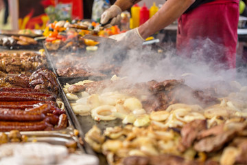 Assorted delicious grilled meat, sausage, potatos with vegetables and cheese on a barbecue