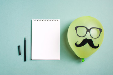 Black paper mustache and glasses on balloon and a notepad with a felt-tip pen Month donations...