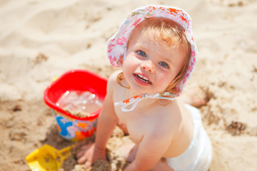 little baby girl  at the beach playing with sand toys