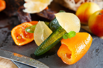 Mix of dried glazed fruits in syrup on wooden background