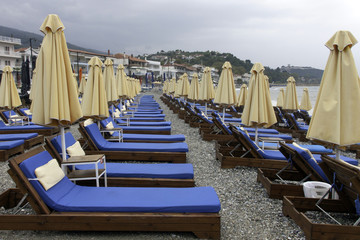 Beach umbrellas and empty lounge chairs on a cloudy day.