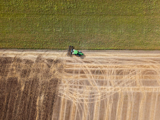 Panoramic view of tractor plowing the soil after harvesting on the field. Top view from drone.
