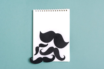 Black paper mustache on a notepad with a felt-tip pen Month donations concept for the study and...