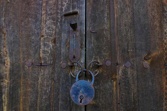 Old rusty opened lock without key. Vintage wooden door, close up concept photo. Security, metal.