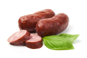 Bratwurst smoked pork sausages with sausage slices and green fresh basil leaves, isolated on white background.