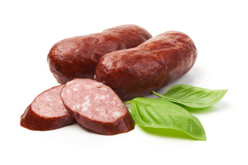 Bratwurst smoked pork sausages with sausage slices and green fresh basil leaves, isolated on white background.