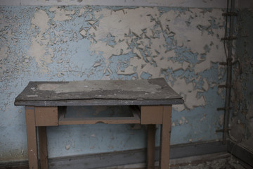 Aging table in front of the wall with peeled of blue paint