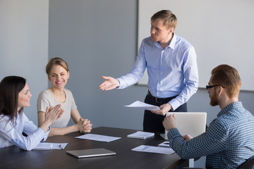 Millennial businessman talking to female worker during company briefing, complimenting for good...