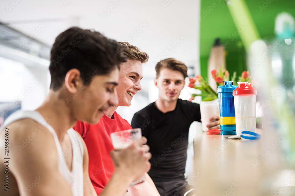 Canvas Prints Men in gym sitting and holding glasses of protein drink.