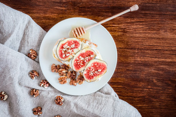 Top view spelt sourdough toast with feta cheese spread, fresh figs with honey, and raw walnut. Vintage wooden table, coarse cloth burlap, rustic style.