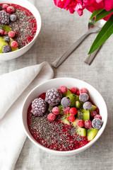 Breakfast smoothie bowl topped with frozen berries and chia seeds, top view