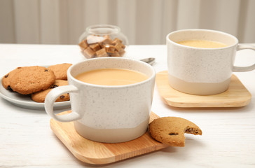 Cups with black tea and milk on table
