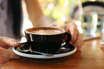 Woman with cup of fresh aromatic coffee at table, closeup